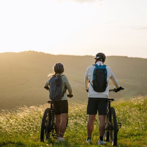 Dwoje rowerzystów na wzgórzu o zachodzie słońca